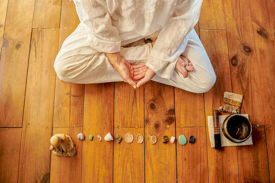 From above of crop unrecognizable barefoot male practicing yoga on floor near bowl gong and Buddha statuette