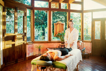 Healer practicing palm healing technique for female client lying on couch during spiritual practice for filling with harmony and energy