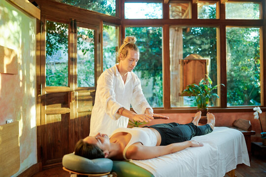 Healer practicing palm healing technique for female client lying on couch during spiritual practice for filling with harmony and energy