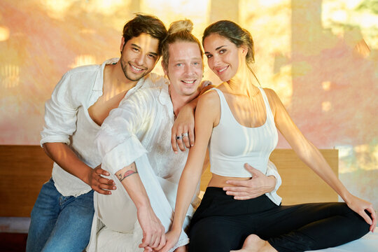 Smiling multiracial couple sitting close to reiki master and embracing each other in  alternative medicine salon