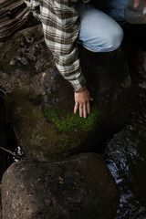 Cropped man crouching on rock by river