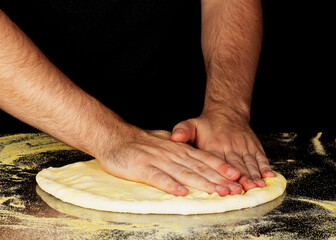 Men's hands or chef kneading dough to prepare or bake pizza or bread