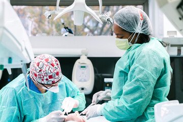 African American nurse assisting professional dentist during procedure with teeth of patient in modern stomatology clinic