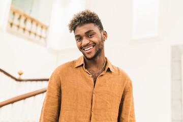 Handsome young bearded hipster black guy with curly hair dressed in casual white shirt looking at camera