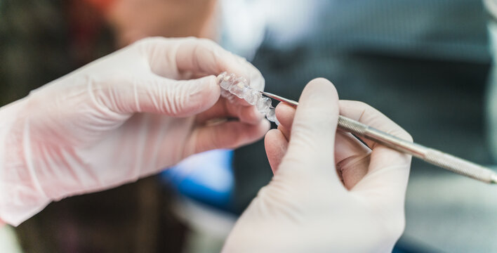 Crop unrecognizable dentist in latex gloves holding ultra thin veneers and scaler while working in dental clinic