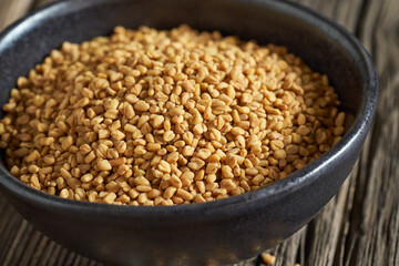 Fenugreek seeds in a black bowl, closeup