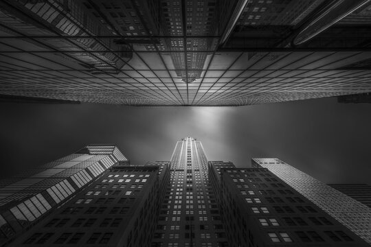 From below exterior of modern high rise buildings with glass mirrored walls under dark blue sky on street of Chicago in USA, black and white picture