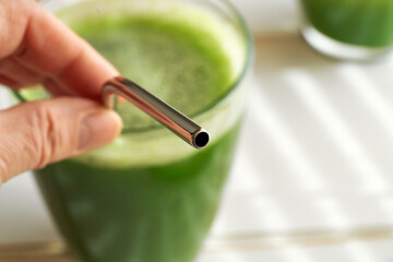 Close up of a stainless steel straw in a glass of green juice - zero waste concept