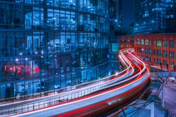 Long exposure of illuminated curvy elevated railroad located in modern district of Chicago city with contemporary multistory glass buildings in twilight time