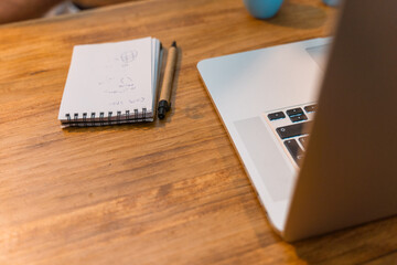 Workplace of freelancer with modern netbook placed on wooden table with cups of espresso and notepad in cafe