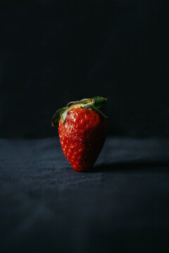 Colorful tasty sweet strawberry with green pedicel on top and tiny seeds on uneven surface