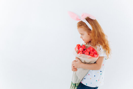 Funny curly girl with bunny ears and flowers on isolated background. Easter holiday concept. Funny curly girl with bunny ears