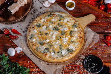 The pizza is on the kitchen table, and the ingredients are scattered around. Pizza 4 cheeses