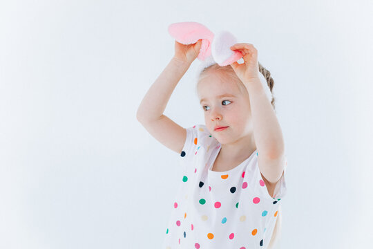 Funny curly girl plays with bunny ears on isolated background. Easter holiday concept