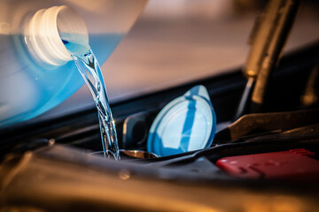 Obraz na płótnie Canvas Pouring blue antifreeze liquid for washing car screen.