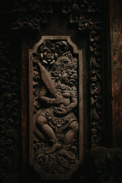 Traditional ornate Balinese relief wall panel with carved patterns and image of Hindu God with sword