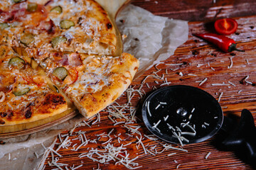 The pizza is on the kitchen table, and the ingredients are scattered around. Pizza with pickles and tomatoes