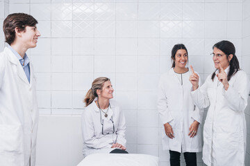 Group of doctors talking to each other in a hospital room and dressed in white coat uniforms