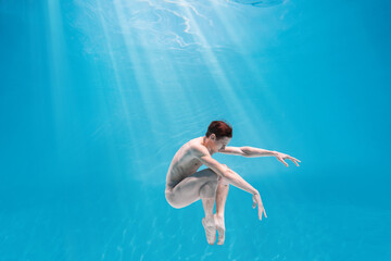 Male Caucasian man swimmer diver dancer swims under water in the sea. Summer tourism, travel journey trip voyage, holiday and vacation. Concertation, art, beauty and freedom concept