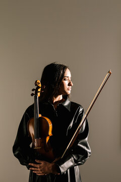 Female violinist standing with musical instrument and thoughtfully closed eyes