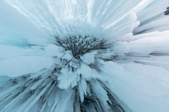 From below of huge icicles hanging from rocky cave near Lake Baikal in winter as abstract background