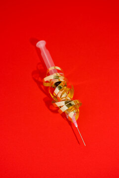 Plastic injector with curved golden ribbon and pointed needle representing celebration gift