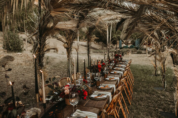 Wooden table served with plates and decorated with flowers in garden for wedding party