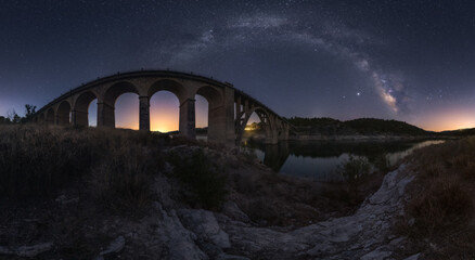 Wide angle of viaduct bridge under night sky with sparkling stars in long exposure