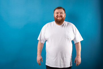 portrait of a bearded cheerful, emotional and interesting man in a white T-shirt on a blue...