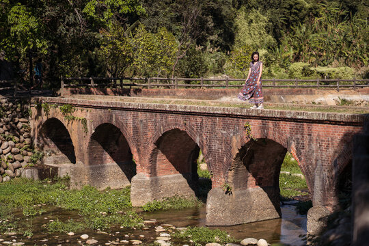 Female in maxi dress standing on Daping Red Bridge during vacation in Taiwan in summer
