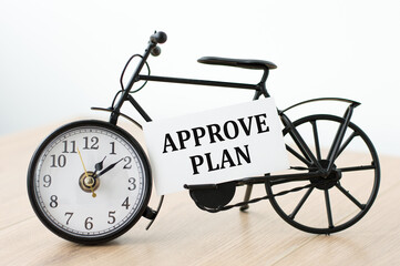A business card with the text APPROVE PLAN with clock on isolated table