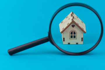 Find a home or a flat concept. Toy model house under magnifying glass. Rent apartments, Real Estate and buying a house idea. Blue background