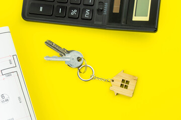Buying a house or mortgage concept. Keys with calculator and plan on yellow background. Housing and Real Estate concept.