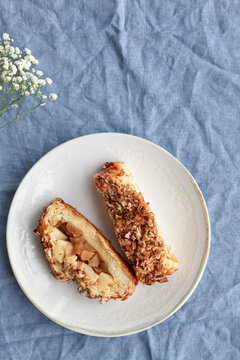 Overhead view of yummy apple pastry on ceramic saucers near fresh flower on creased textile