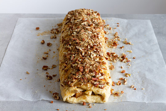 From above tasty apple pastry with crunchy nut pieces on baking paper on countertop