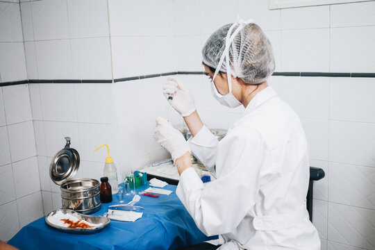 Doctor sitting in front of a table with different tools to operate in an operating room filling a needle with anesthesia