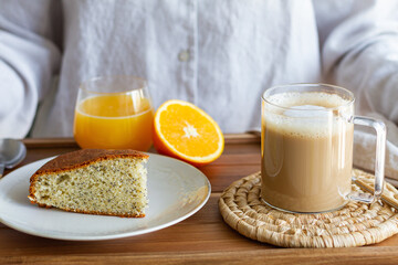 Unrecognizable crop woman with wooden tray served with cup of coffee and sponge cake for breakfast at home