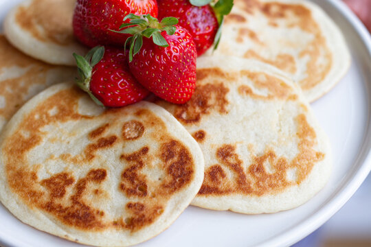 Closeup of homemade pancakes with fresh strawberries served on plate on table for healthy breakfast