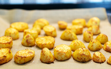 Golden fried potato wedges baked on a baking sheet in the oven