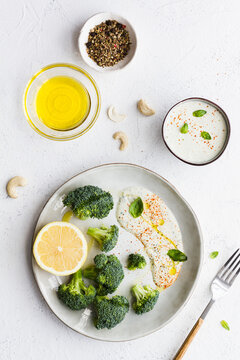 Top view of tasty broccoli with fresh lemon and sauce near bowls with olive oil and spice mix on table