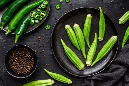 Top view of ripe green superfood on ceramic black plates near pepper in bowl on table