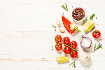 Food cooking background on white wooden table. Fresh vegetables, spices, herbs and oil. Ingredients for cooking. Top view with copy space.