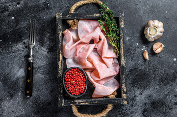Thin sliced Smoked  pork ham in wooden tray. Black background. Top view