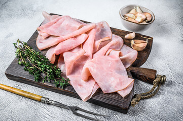 Ham Thin sliced on wooden cutting board with herbs. White background. Top view