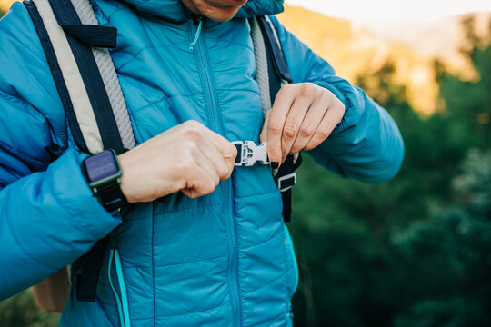 Crop anonymous explorer standing in nature and clasping plastic fastener of backpack during trekking in nature