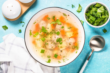 Meatballs soup with vegetables. Traditional Ukrainian dish. Top view on light table.