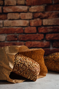 Tasty whole bread with brown crust and sunflower seeds on top on table in daylight