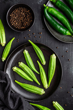 Top view of ripe green superfood on ceramic black plates near pepper in bowl on table