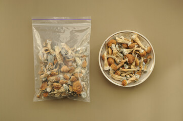 Psilocybin Psilocybe Cubensis mushrooms in a plastic bag on brown soft background. Psychedelic...