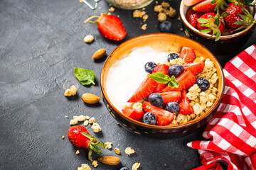 Greek yogurt granola with fresh berries on black stone table.